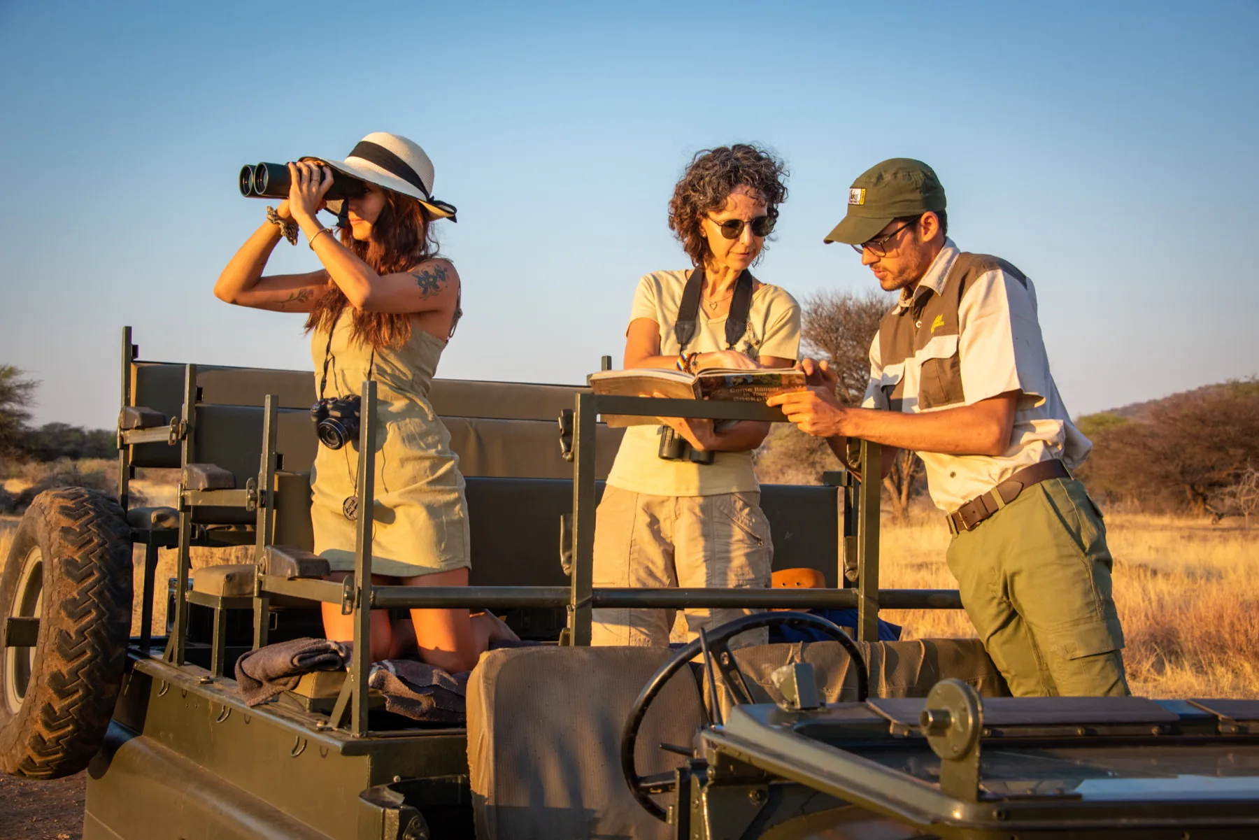 Guests and an expert guide planning a safari beside an open vehicle