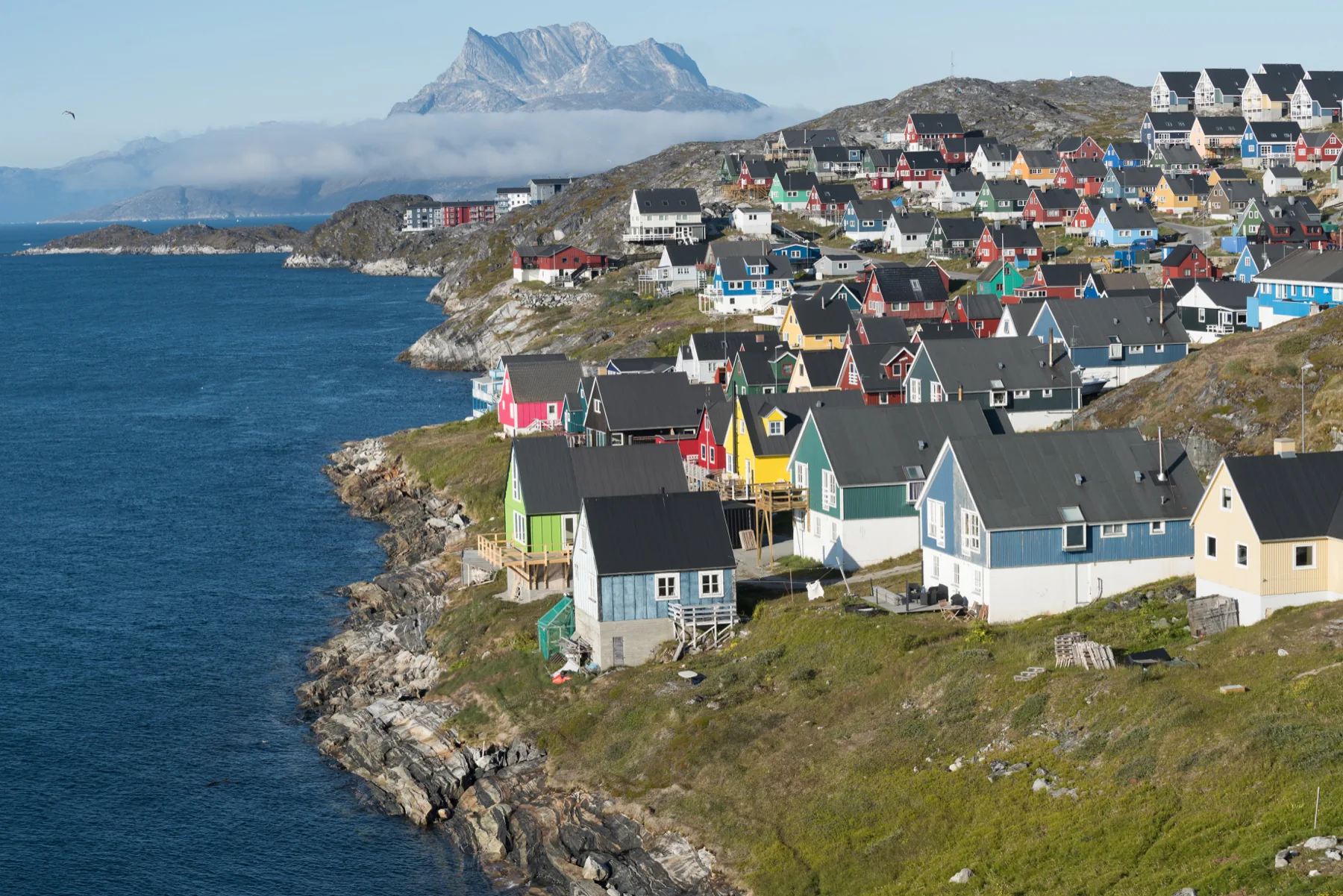 Colourful Greenlandic houses overlooking a rocky coastline and mountains