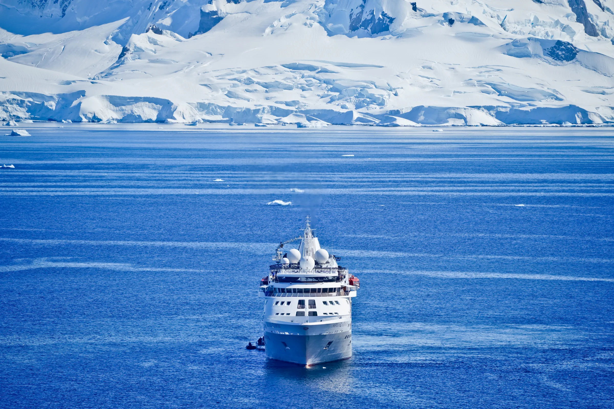 Expedition ship sailing towards a vast Arctic glacier