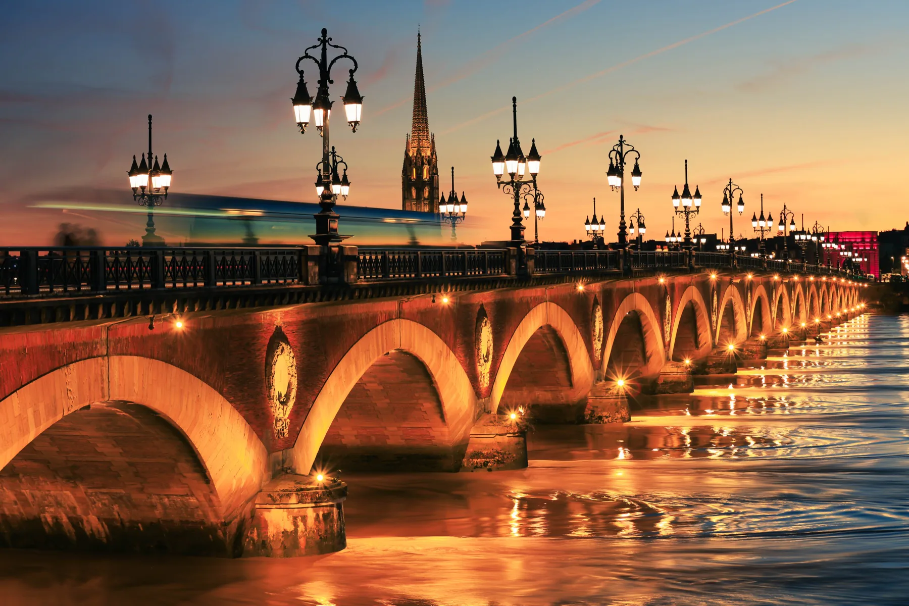 Historic European bridge and city lights reflected in the river at sunset