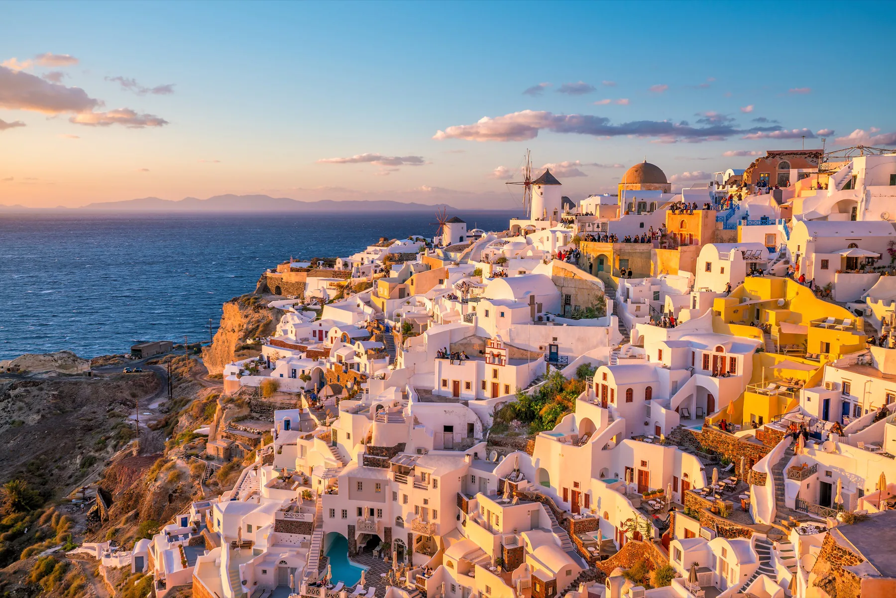 Whitewashed buildings and windmills overlooking the sea in Santorini at sunset