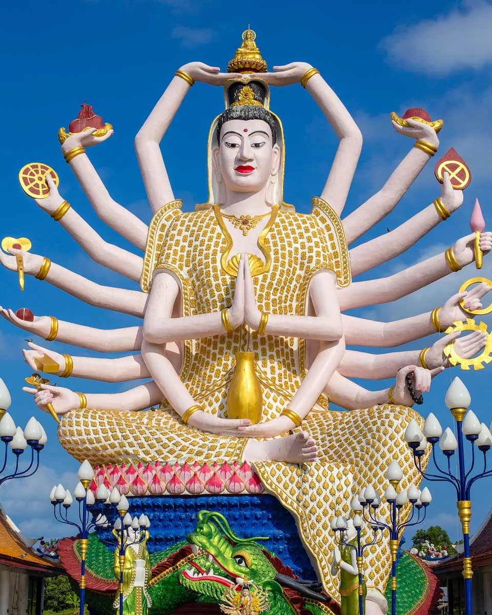 Many-armed Buddhist statue beneath a deep blue sky in Thailand