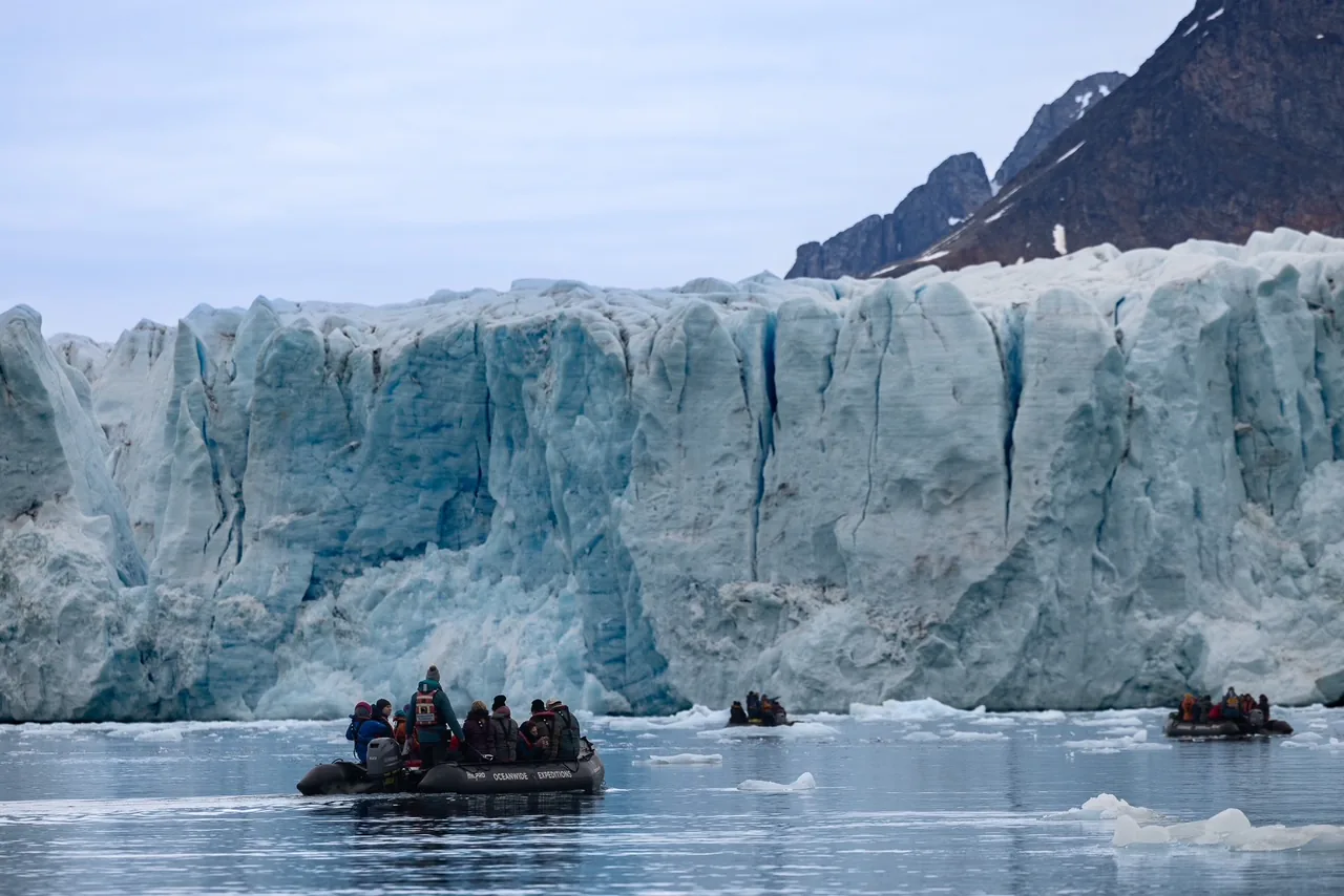Travellers exploring a dramatic coastal glacier