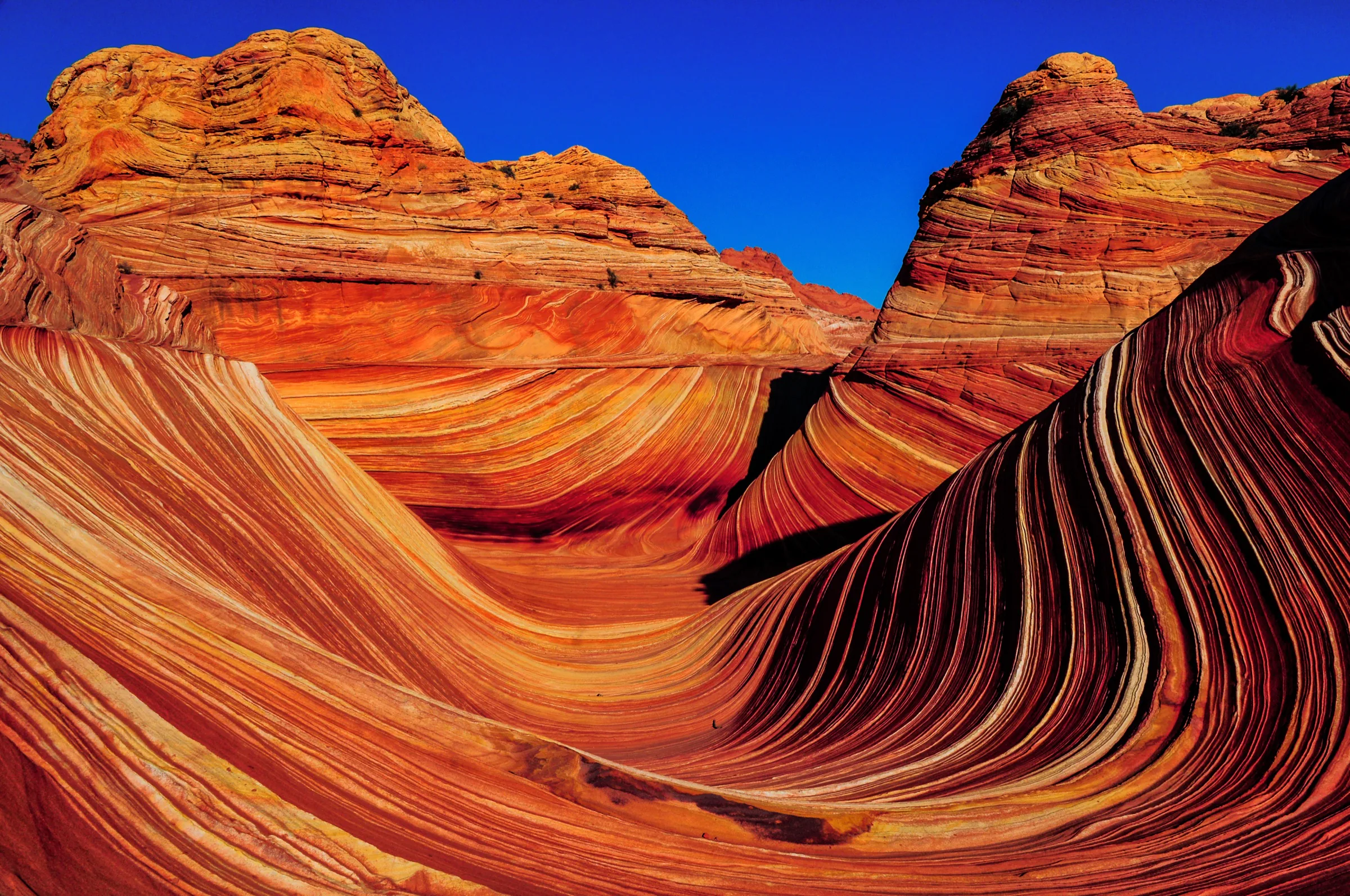 Sweeping layers of red and orange sandstone beneath a deep blue sky